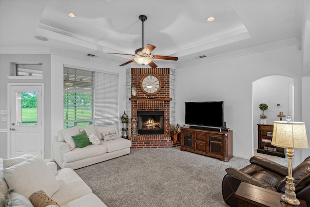12319 N Emerald Ranch Ln, Forney, TX 75126 - living room with arched walkways, a raised ceiling, ceiling fan, a brick fireplace, and ornamental molding