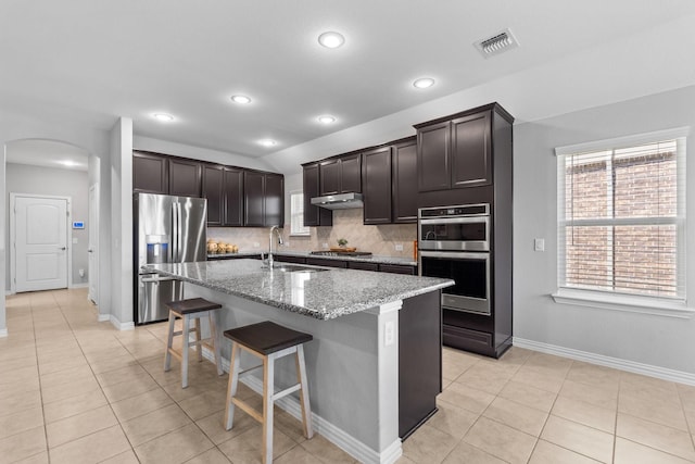 952 Sweeping Butte Dr, Fort Worth, TX 76052 - kitchen with stainless steel appliances, a sink, arched walkways, under cabinet range hood, and tasteful backsplash