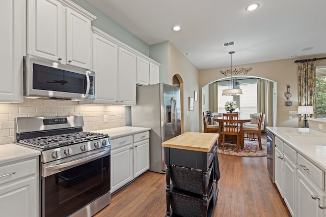936 Medinah Dr, Fairview, TX 75069 - kitchen featuring appliances with stainless steel finishes, arched walkways, butcher block counters, white cabinets, and recessed lighting