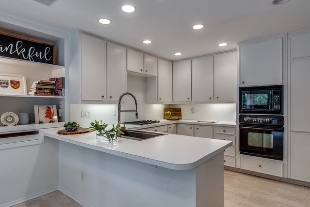 9616 Viewside Dr, Dallas, TX 75231 - kitchen with black appliances, a peninsula, recessed lighting, light countertops, and a sink