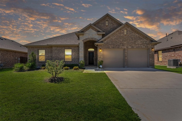 3640 Twin Pines Dr, Grand Prairie, TX 76065 - french country inspired facade featuring central AC, brick siding, an attached garage, driveway, and a lawn
