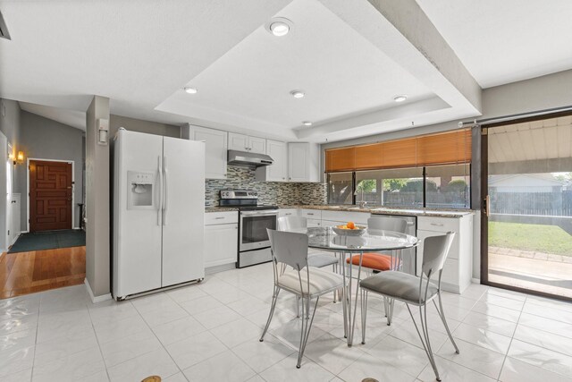 4028 Engleman St, Fort Worth, TX 76137 - kitchen with stainless steel appliances, under cabinet range hood, a tray ceiling, decorative backsplash, and recessed lighting
