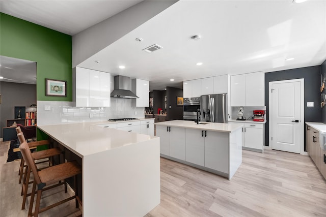 9918 Ila Dr, Dallas, TX 75220 - kitchen featuring wall chimney exhaust hood, stainless steel fridge with ice dispenser, gas stovetop, modern cabinets, and a peninsula
