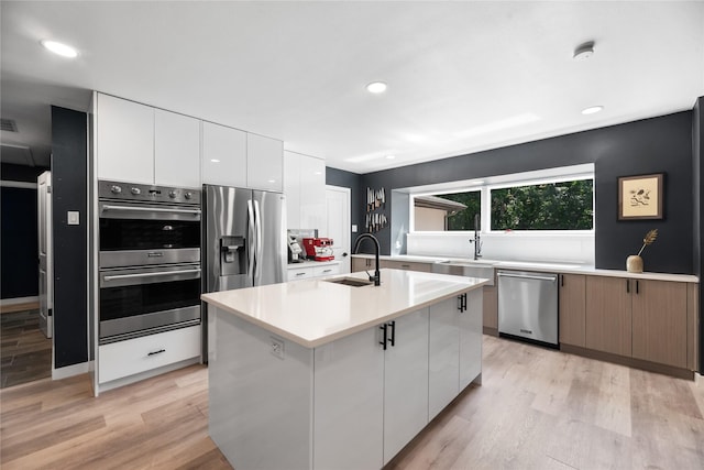 9918 Ila Dr, Dallas, TX 75220 - kitchen with appliances with stainless steel finishes, a sink, modern cabinets, light wood-style flooring, and light countertops