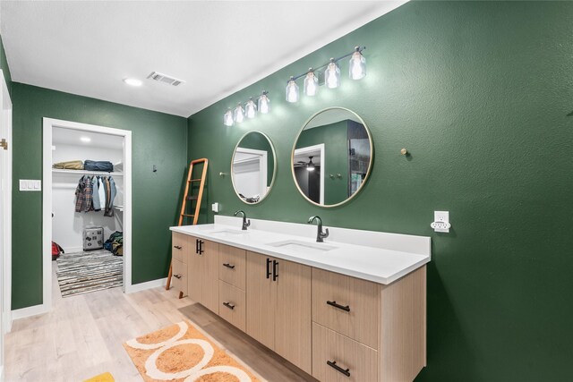 9918 Ila Dr, Dallas, TX 75220 - bathroom featuring double vanity, wood finished floors, a walk in closet, and baseboards