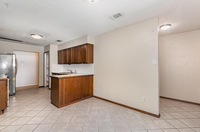 1824 Angelina Dr, Garland, TX 75040 - kitchen featuring light countertops, freestanding refrigerator, light tile patterned floors, a textured ceiling, and a sink
