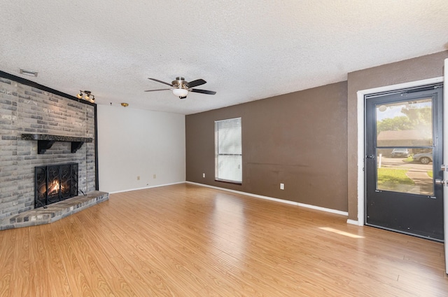 1824 Angelina Dr, Garland, TX 75040 - unfurnished living room with ceiling fan, wood finished floors, a textured ceiling, healthy amount of natural light, and a brick fireplace