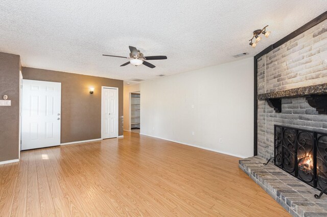 1824 Angelina Dr, Garland, TX 75040 - unfurnished living room with ceiling fan, wood finished floors, a brick fireplace, baseboards, and a textured ceiling