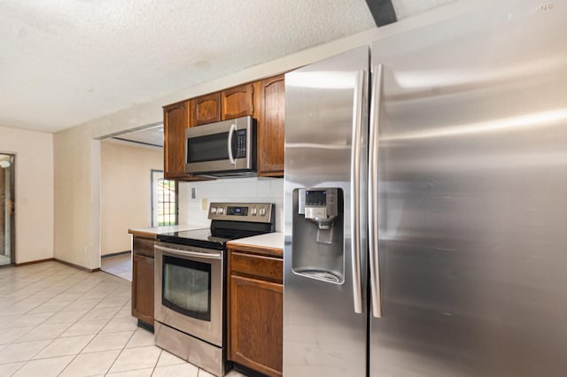 1824 Angelina Dr, Garland, TX 75040 - kitchen with appliances with stainless steel finishes, light countertops, light tile patterned flooring, a textured ceiling, and baseboards