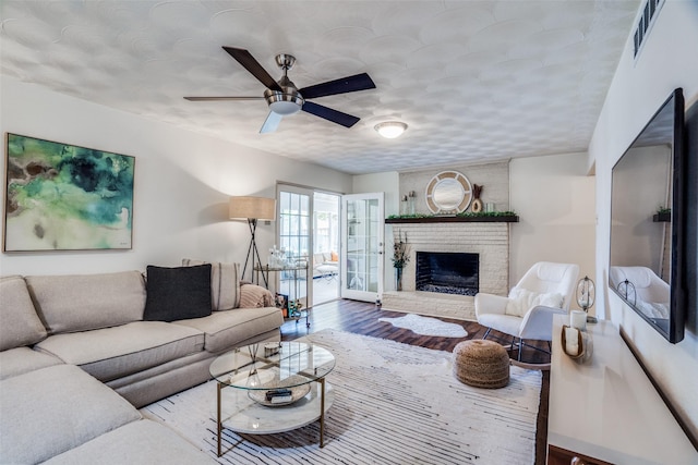 10542 Vinemont St, Dallas, TX 75218 - living room featuring ceiling fan, wood finished floors, a fireplace, and a textured ceiling