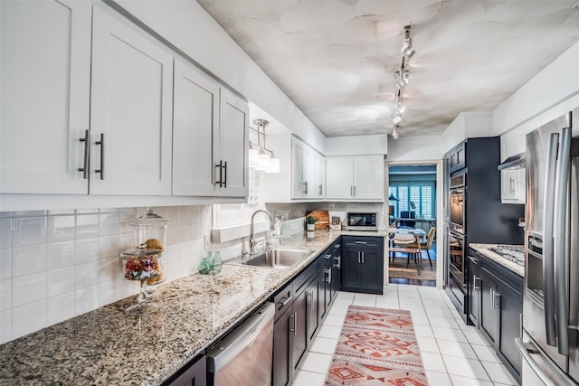 10542 Vinemont St, Dallas, TX 75218 - kitchen with stainless steel appliances, a sink, light tile patterned flooring, tasteful backsplash, and rail lighting