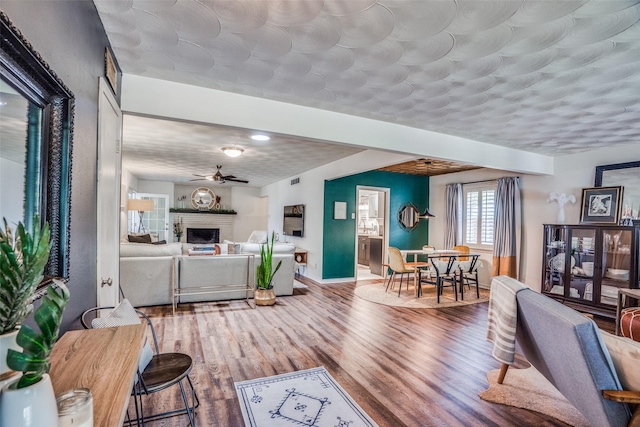 10542 Vinemont St, Dallas, TX 75218 - living area featuring a fireplace, wood finished floors, baseboards, and a ceiling fan
