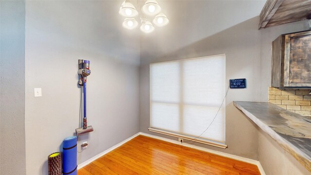 7409 Pebble Beach Dr, Rowlett, TX 75088 - unfurnished dining area with wood finished floors, a chandelier, and baseboards