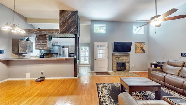 7409 Pebble Beach Dr, Rowlett, TX 75088 - living area featuring a high ceiling, a ceiling fan, wood finished floors, baseboards, and a stone fireplace