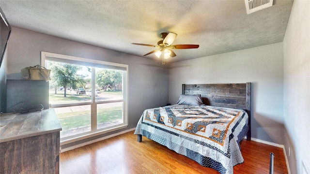 7409 Pebble Beach Dr, Rowlett, TX 75088 - bedroom with wood finished floors, baseboards, a ceiling fan, and a textured ceiling