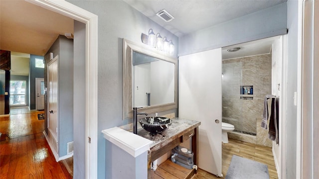 7409 Pebble Beach Dr, Rowlett, TX 75088 - full bath featuring wood-type flooring, tiled shower, toilet, and vanity