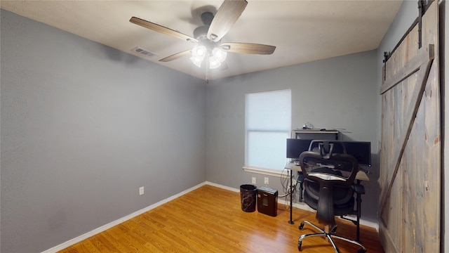 7409 Pebble Beach Dr, Rowlett, TX 75088 - home office featuring a barn door, wood finished floors, a ceiling fan, and baseboards