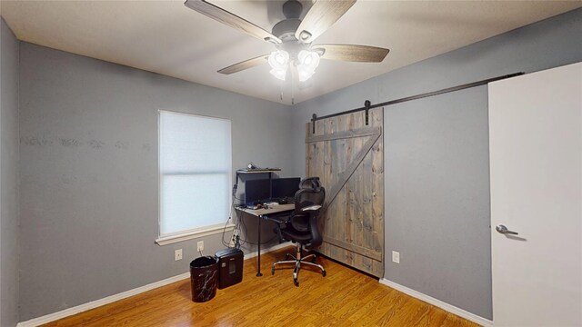 7409 Pebble Beach Dr, Rowlett, TX 75088 - home office featuring wood finished floors, a barn door, baseboards, and ceiling fan