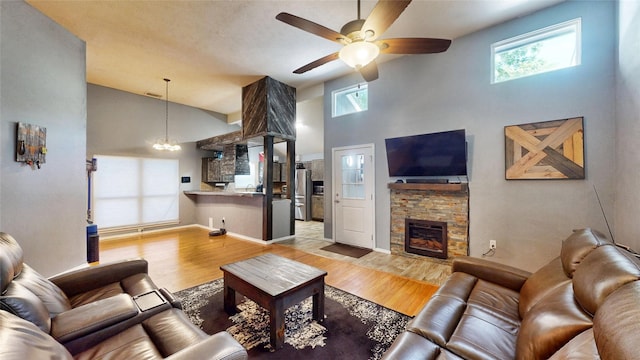 7409 Pebble Beach Dr, Rowlett, TX 75088 - living room featuring a ceiling fan, a towering ceiling, light wood-style floors, a stone fireplace, and a chandelier
