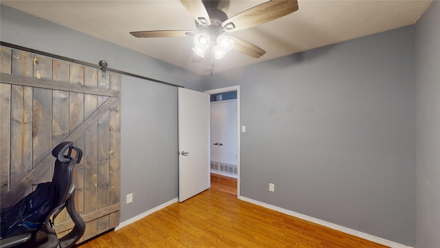 7409 Pebble Beach Dr, Rowlett, TX 75088 - home office with wood finished floors, ceiling fan, baseboards, and a barn door