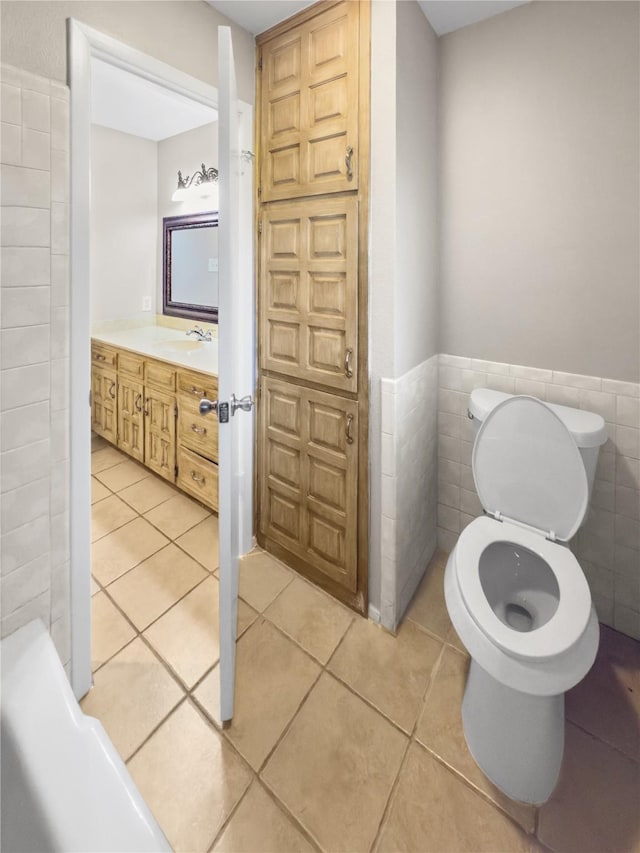 7636 Skylake Dr, Fort Worth, TX 76179 - bathroom featuring tile patterned floors, tile walls, toilet, vanity, and wainscoting