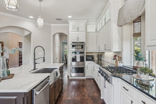 5594 Beacon Hill Dr, Frisco, TX 75036 - kitchen with appliances with stainless steel finishes, a sink, arched walkways, white cabinetry, and dark stone countertops