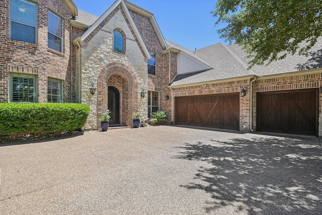 5594 Beacon Hill Dr, Frisco, TX 75036 - french country home with driveway, a garage, a shingled roof, and brick siding