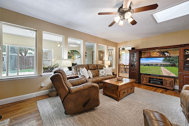 2112 Columbia Dr, Richardson, TX 75081 - living room with a ceiling fan, light wood-style floors, a skylight, and baseboards