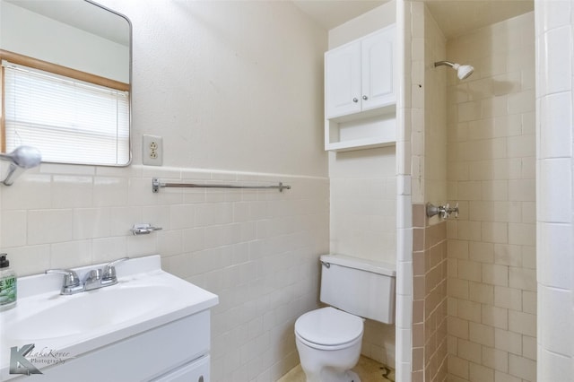 2757 Old Anson Rd, Abilene, TX 79603 - full bathroom featuring a tile shower, toilet, vanity, tile walls, and a wainscoted wall