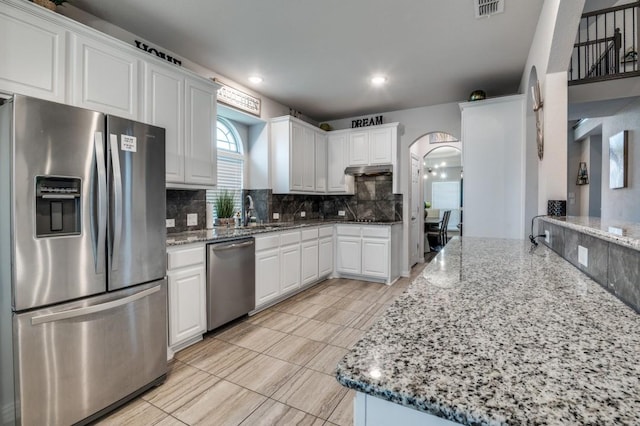 249 Noble Nest Dr, Midlothian, TX 76065 - kitchen featuring appliances with stainless steel finishes, arched walkways, decorative backsplash, a sink, and white cabinets