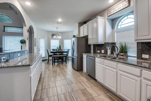 249 Noble Nest Dr, Midlothian, TX 76065 - kitchen with stainless steel appliances, a sink, white cabinetry, arched walkways, and tasteful backsplash