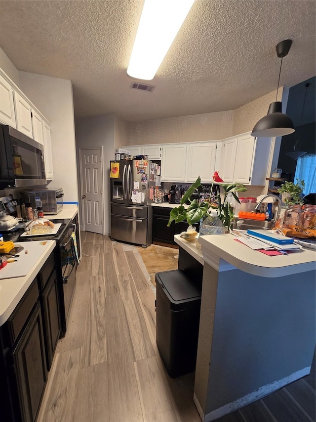 2006 Cori Pl, Sachse, TX 75048 - kitchen with appliances with stainless steel finishes, light wood-type flooring, light countertops, white cabinetry, and a textured ceiling