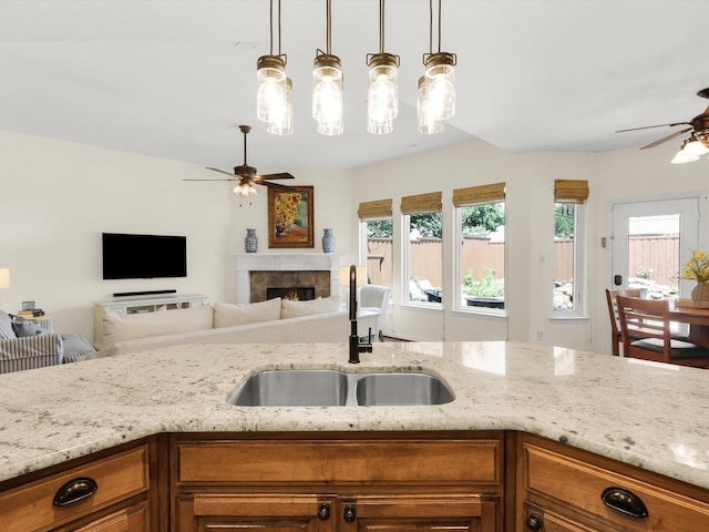 2525 Still Springs Dr, Little Elm, TX 75068 - kitchen with a ceiling fan, a sink, brown cabinets, and light stone counters