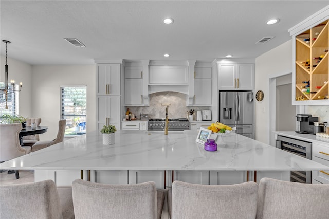 125 Wood Bend Ct, Weatherford, TX 76087 - kitchen with appliances with stainless steel finishes, beverage cooler, tasteful backsplash, a chandelier, and white cabinets