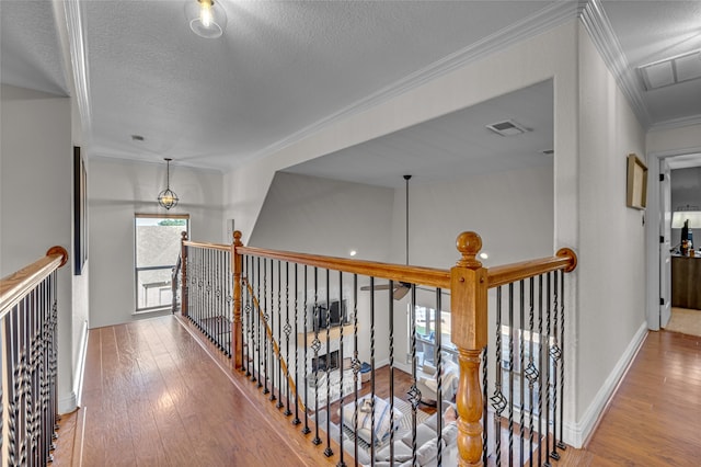 125 Wood Bend Ct, Weatherford, TX 76087 - hall with wood-type flooring, ornamental molding, a textured ceiling, baseboards, and an upstairs landing
