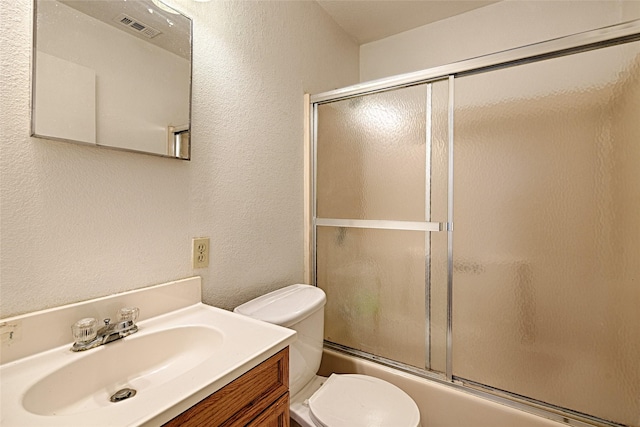 1705 Savoy St, Dallas, TX 75224 - bathroom with a textured wall, toilet, vanity, and shower / bath combination with glass door