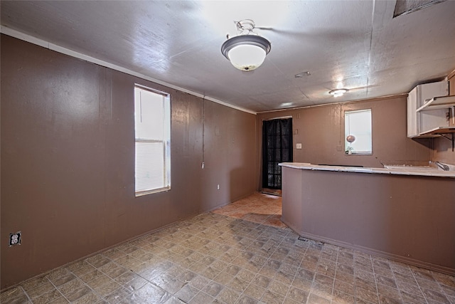 1705 Savoy St, Dallas, TX 75224 - kitchen featuring light countertops, open shelves, a peninsula, light floors, and white cabinets
