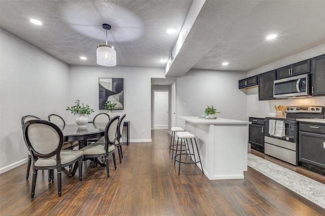 3321 NW 31st St, Fort Worth, TX 76106 - kitchen featuring stainless steel appliances, light countertops, baseboards, a kitchen bar, and dark wood-type flooring