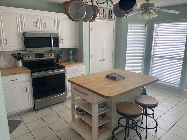 5907 Aloe Ct, Arlington, TX 76017 - kitchen featuring appliances with stainless steel finishes, butcher block counters, light tile patterned flooring, and white cabinetry