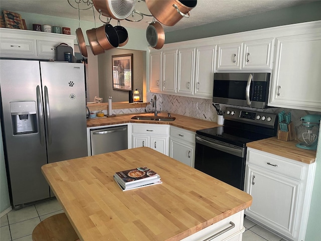 5907 Aloe Ct, Arlington, TX 76017 - kitchen featuring butcher block countertops, appliances with stainless steel finishes, light tile patterned floors, and white cabinets