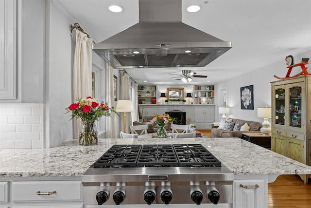 4304 Warnock Ct, Fort Worth, TX 76109 - kitchen with stainless steel gas cooktop, ceiling fan, island range hood, open floor plan, and light stone countertops