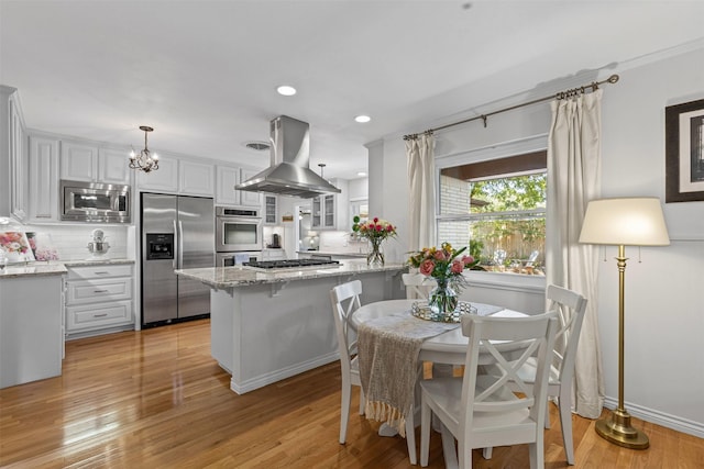 4304 Warnock Ct, Fort Worth, TX 76109 - kitchen featuring appliances with stainless steel finishes, island range hood, white cabinetry, light stone countertops, and recessed lighting
