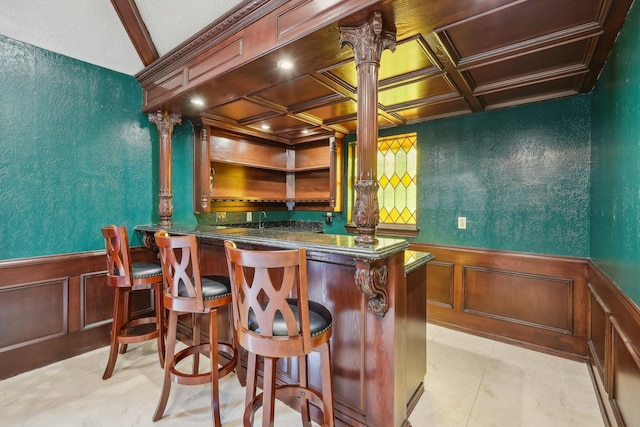 906 Greenbriar Ln, Duncanville, TX 75137 - indoor bar featuring a wainscoted wall, coffered ceiling, a textured wall, decorative columns, and a decorative wall
