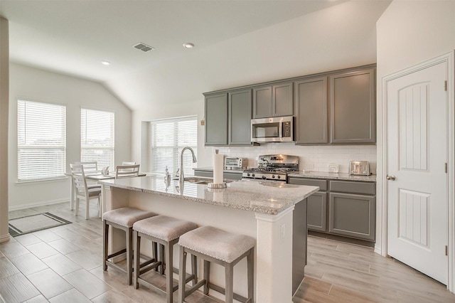 7200 Paso Verde Dr, Fort Worth, TX 76131 - kitchen with stainless steel appliances, lofted ceiling, tasteful backsplash, an island with sink, and a breakfast bar