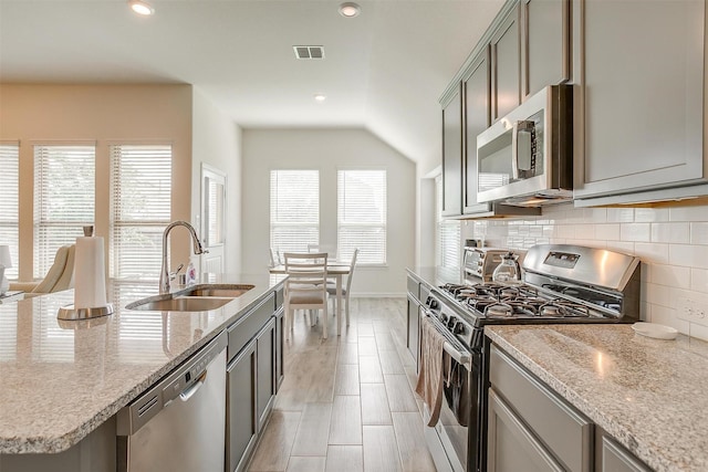 7200 Paso Verde Dr, Fort Worth, TX 76131 - kitchen featuring appliances with stainless steel finishes, a sink, decorative backsplash, vaulted ceiling, and light stone countertops