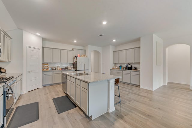 10213 Plumlee Ln, Aubrey, TX 76227 - kitchen with arched walkways, gray cabinetry, appliances with stainless steel finishes, a sink, and tasteful backsplash