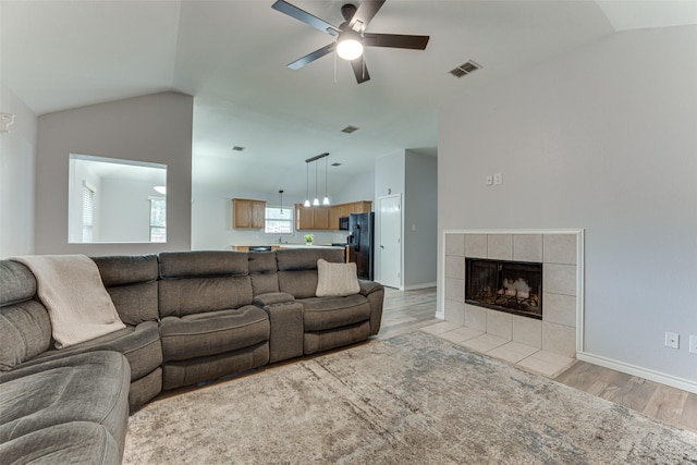 1900 Clear Creek Dr, Little Elm, TX 75068 - living area with vaulted ceiling, light wood-style floors, ceiling fan, a tile fireplace, and baseboards