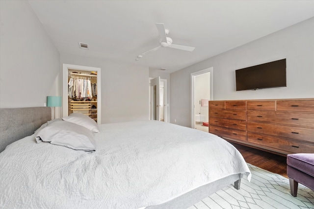 133 Lakeridge Dr, Dallas, TX 75218 - bedroom featuring wood finished floors, a walk in closet, a ceiling fan, a closet, and ensuite bathroom
