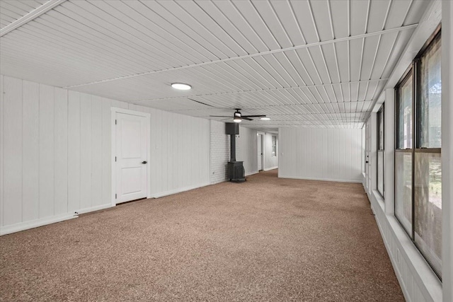607 Audrey Ave, Waco, TX 76705 - unfurnished living room featuring a wood stove, carpet flooring, a ceiling fan, and wood walls