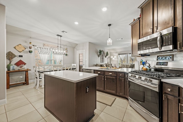 11013 Cobalt Dr, Aubrey, TX 76227 - kitchen featuring stainless steel appliances, a sink, a center island, light tile patterned floors, and dark brown cabinets